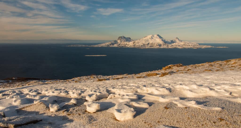 Snødekte fjell og havutsikt i Nord-Norge.