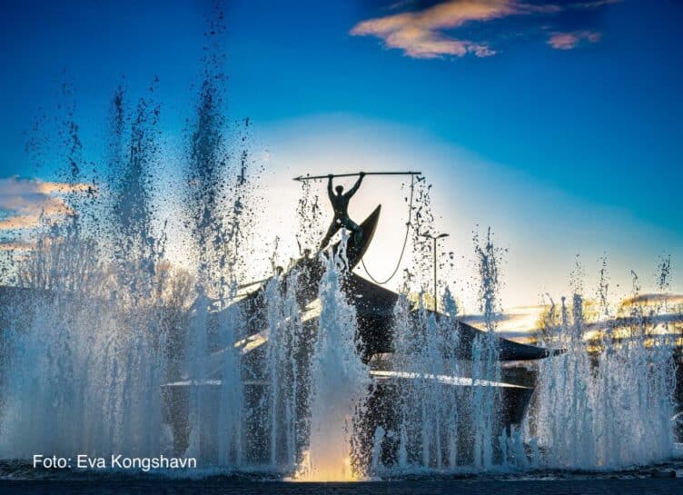 Hvalfangstmonumentet, fonteneskulptur med vannstråler i en park ved solnedgang.