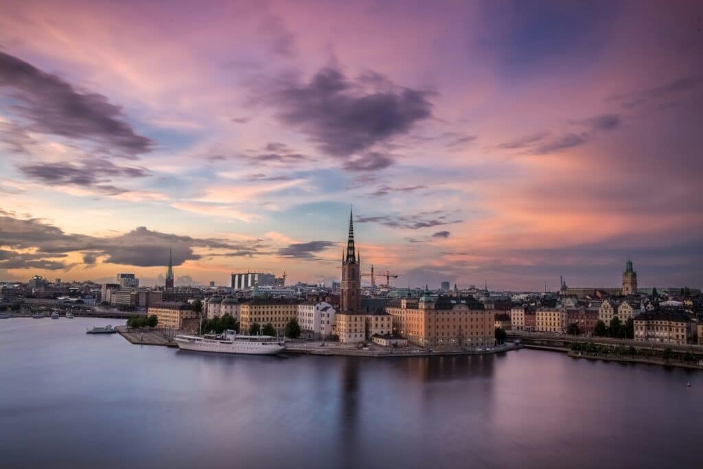 Photo by Raphael Andres on Unsplash Bilde som viser Stockholm by med en rødlig himmel over.