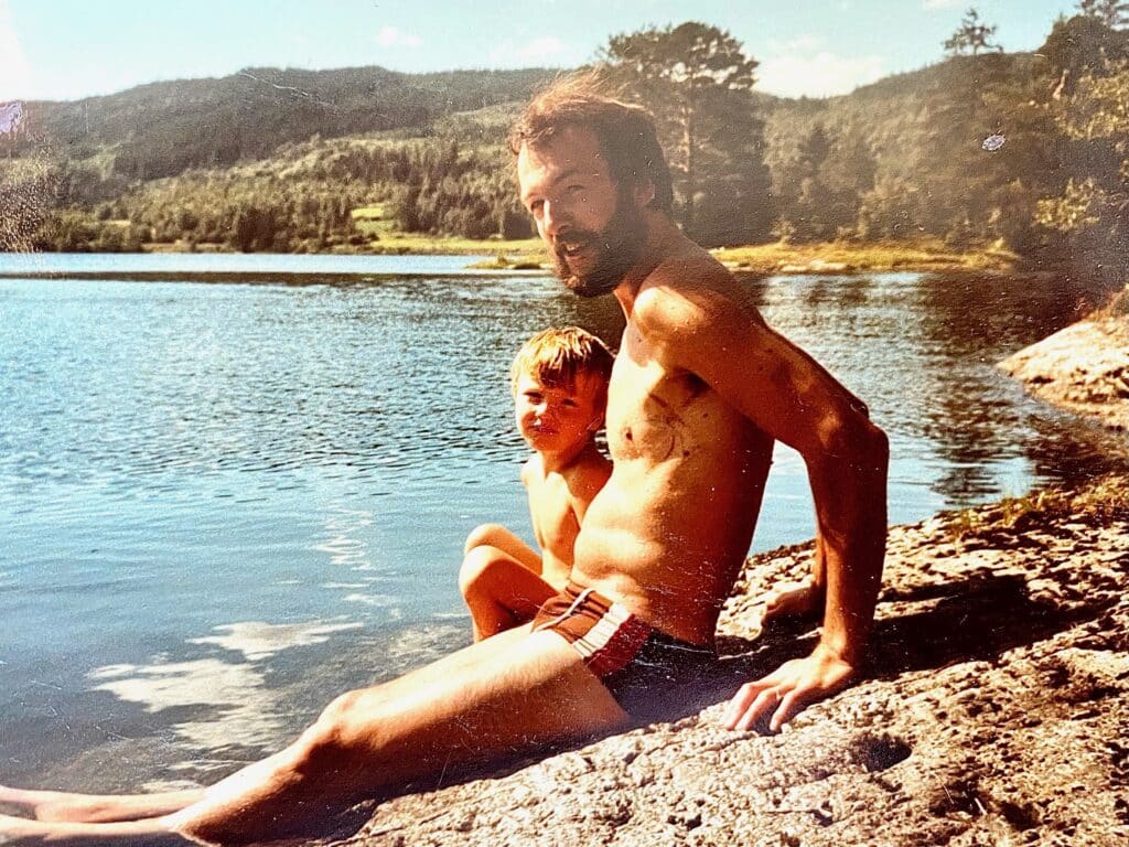 Bilde som viser Eirik og pappen Ketil. De sitter på et svaberg med sjøen i bakgrunn.