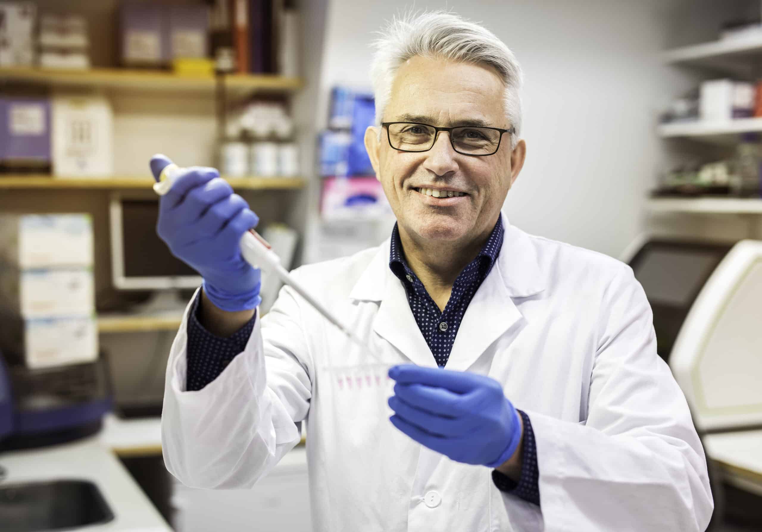 bilde av forsker kjell morten myhr på laben som heller en prøve over i et reagensglass